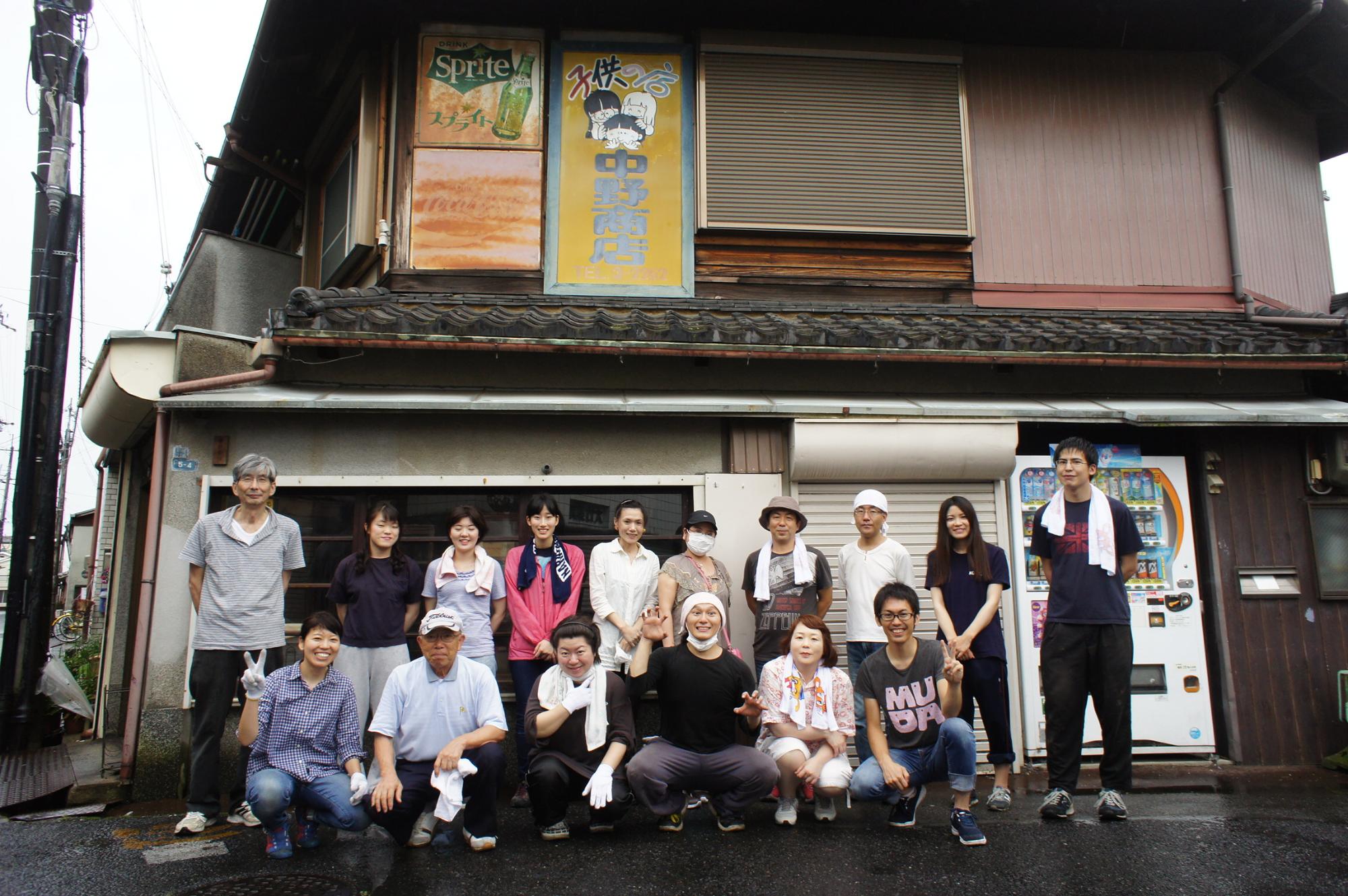 中野商店を背景に、前列に6人・後列に10人が並び集合写真を撮る様子