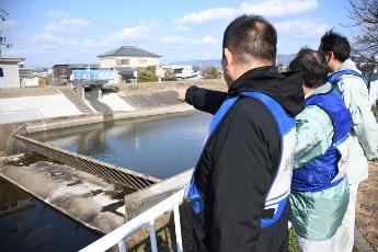 防災訓練の様子（職員と河川を確認する市長の写真）