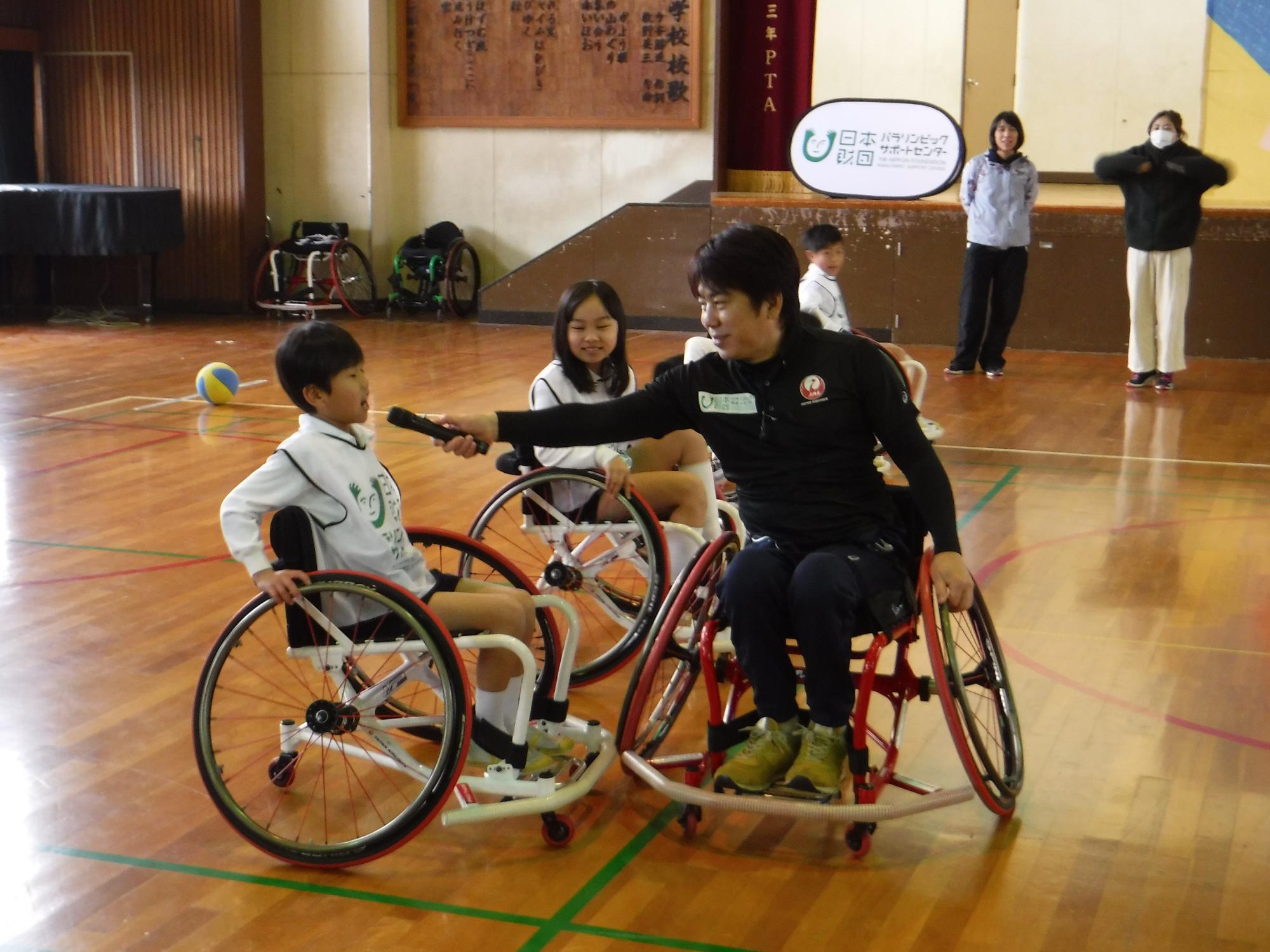 根木慎志さんにインタビューを受ける白いユニフォームを着た男の子の写真