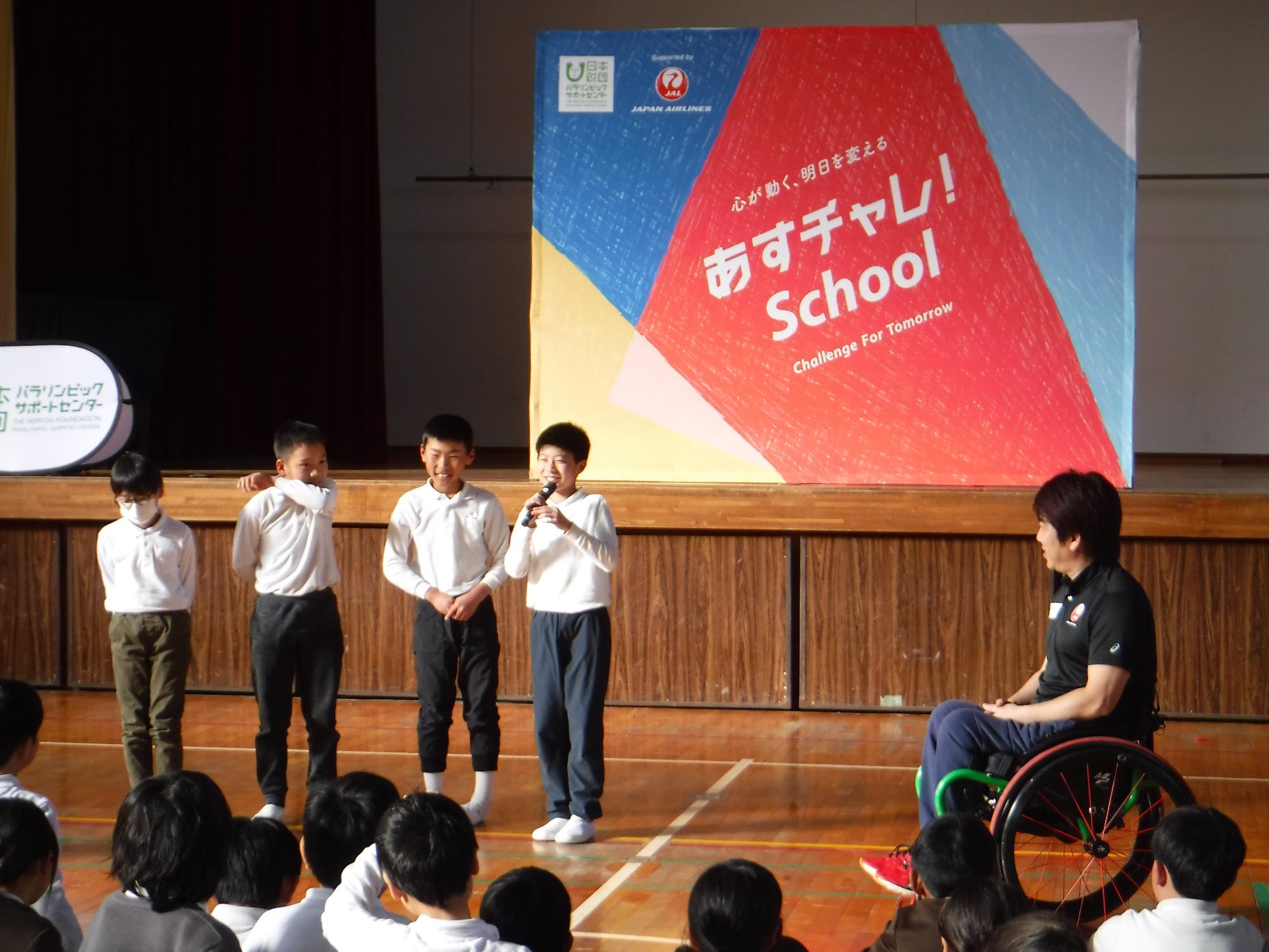 小学生4人が他の小学生たちの前に立ち、うち1人がマイクを持って感想を述べている写真