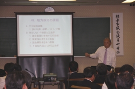 スライドを指しながら講義を行う中邨章氏の写真