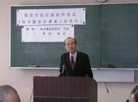 講演台の前に立つ野村稔氏の写真