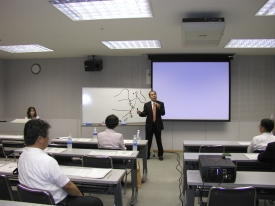 ホワイトボードの前で講義を行う山田勝久氏の写真