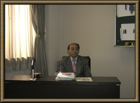机の前で座っている中川幾郎先生の写真