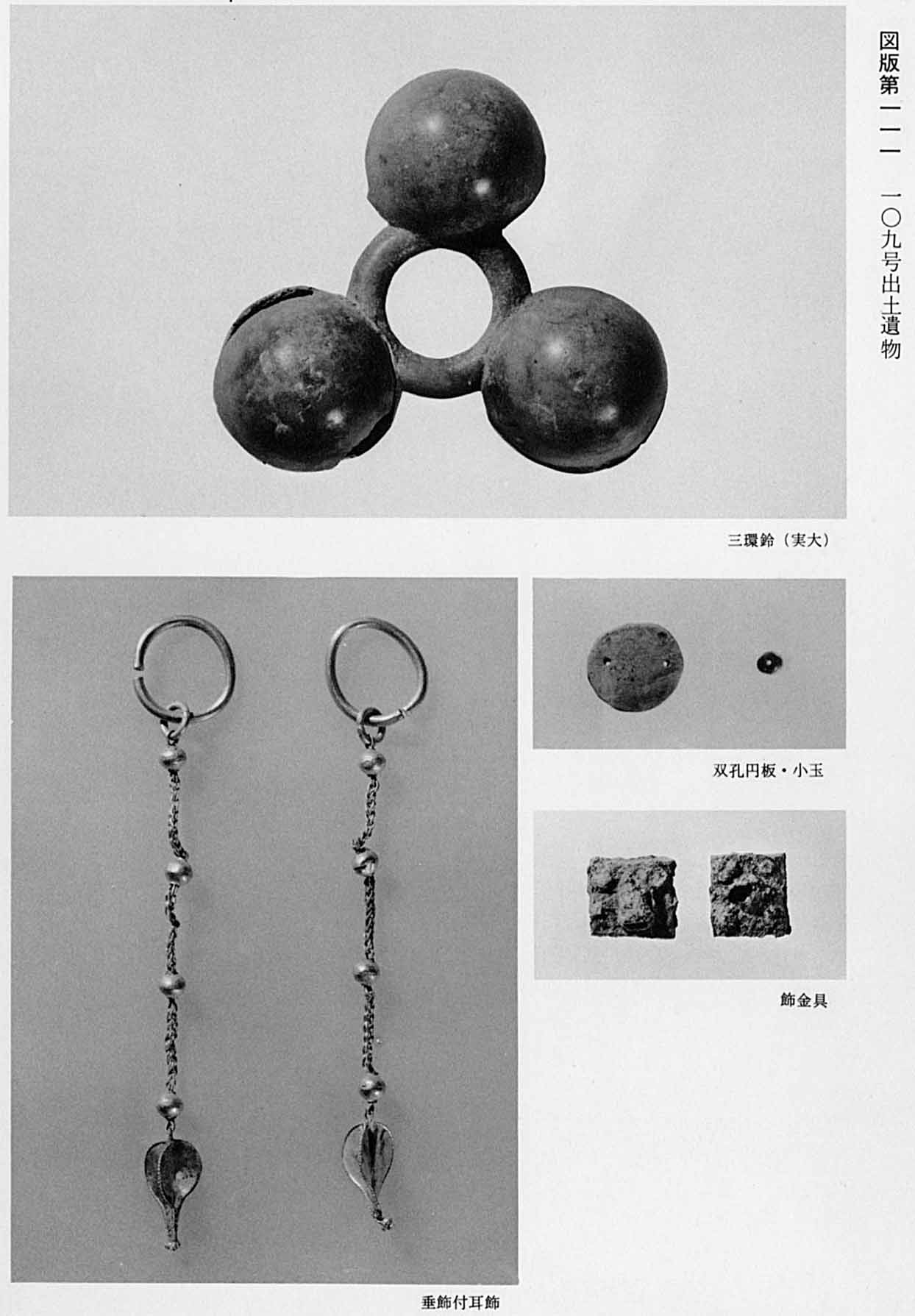 玉が3つ輪で繋がっている鈴と、飾りがたれている古代のイヤリングと、穴が2つ空いている円盤と、正方形の金具がそれぞれ撮影されている、図版111 109号遺物出土遺物のモノクロ写真