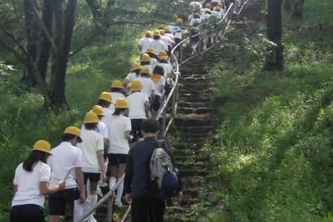 黄色い帽子を被った沢山の生徒たちが、2列に並びながら集団で階段を登っているときの写真