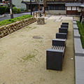 植物と石のパーテーションと瓦の塀の間の敷地にベンチが置かれている写真