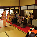 広い茶室で振る舞われたお茶を頂いている和服の男女の様子を撮影した写真