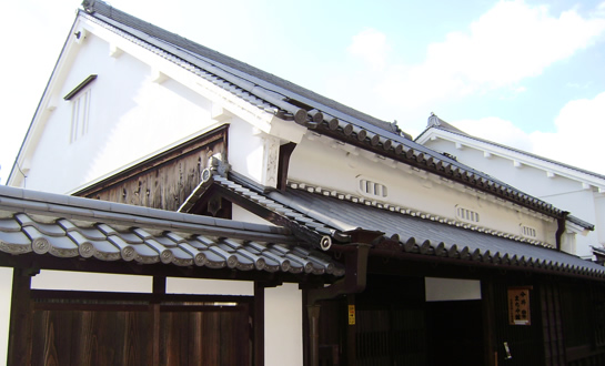 瓦屋根に白い壁で木製の部分もある建物の入口の写真