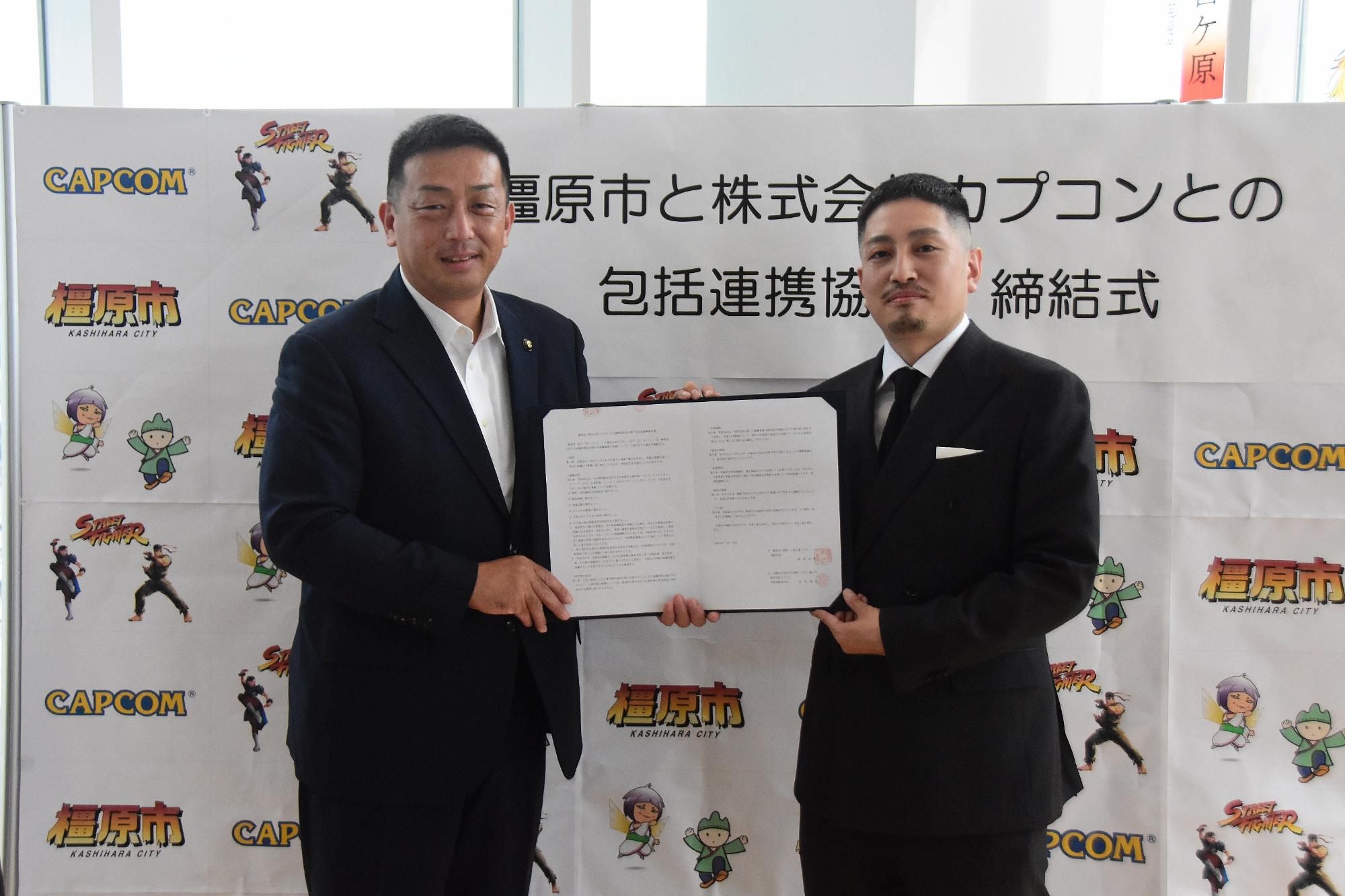橿原市長と「ストリートファイター」シリーズプロデューサー松本脩平さんが協定書を一緒に持っている写真