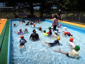 幼稚園のプールで水遊びを楽しんでいる写真