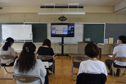 先生たちが教室の中央に置かれたモニターを見ながら研修を受けている写真