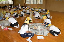 5年生の生徒たちが新聞紙を広げて工作をしているときの写真