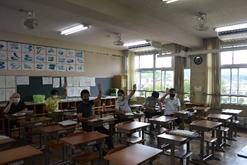 先生たちが教室で研修を受けながら手を挙げている写真