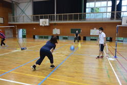 女性の先生が体育館でパイロンに向かってボールを投げている写真