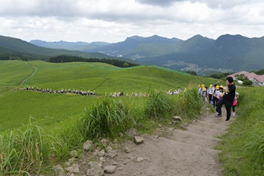 山々を背景になだらかな丘を歩いている5年生の生徒たちの写真